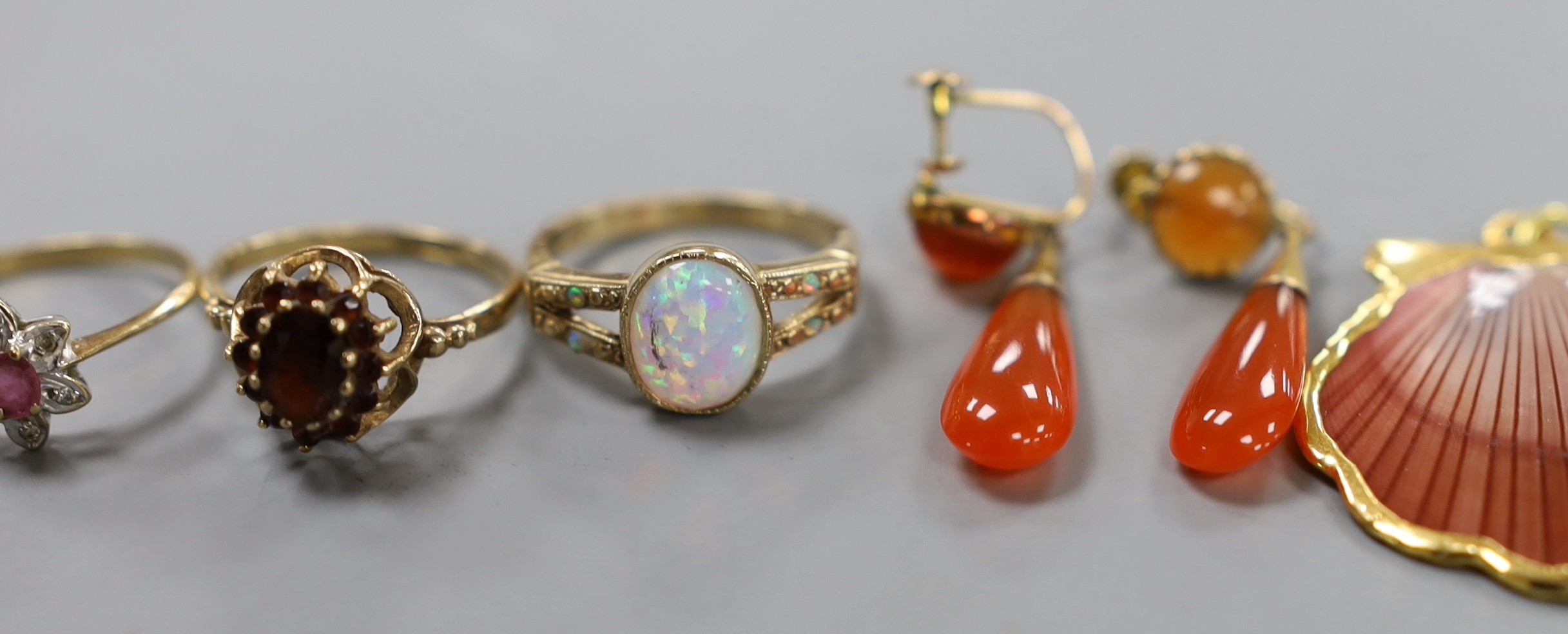 Eight assorted modern 9ct gold and gem set dress rings, a pair of 9ct and carnelian set drop earrings, gross weight 30.7 grams. and a yellow metal mounted shell pendant.